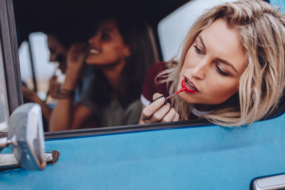 woman putting makeup on traveling