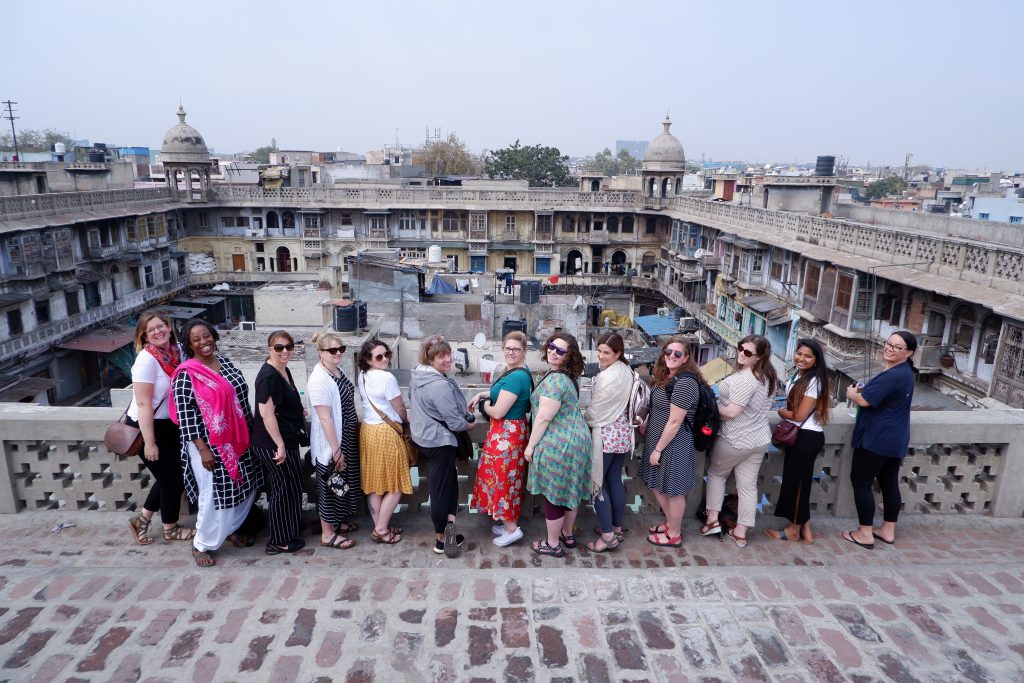 Group of female tourists smiling at a historic monument in Delhi