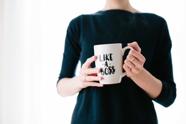 Person wearing a black garment holds a white cup with text like a boss printed on it.