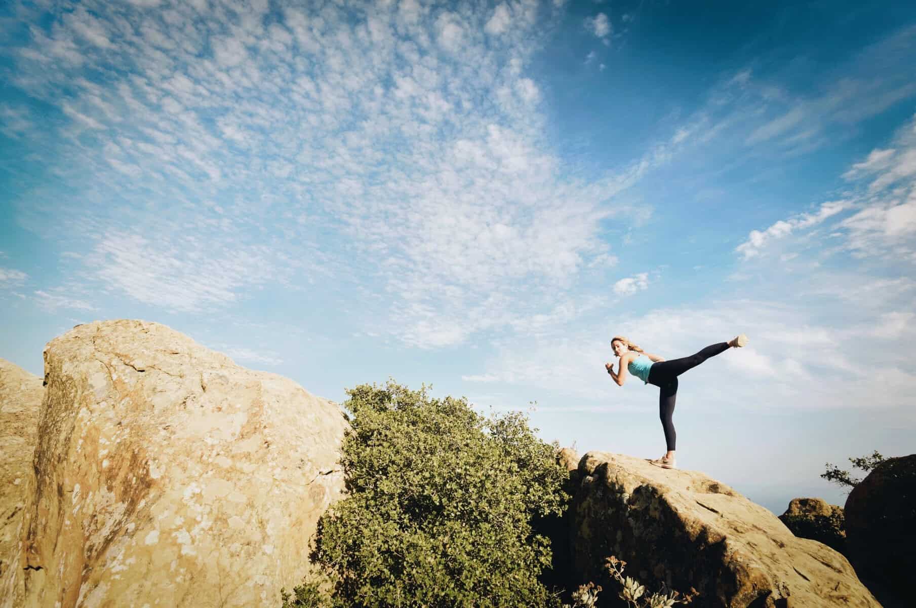 Woman exercising on top of a rock