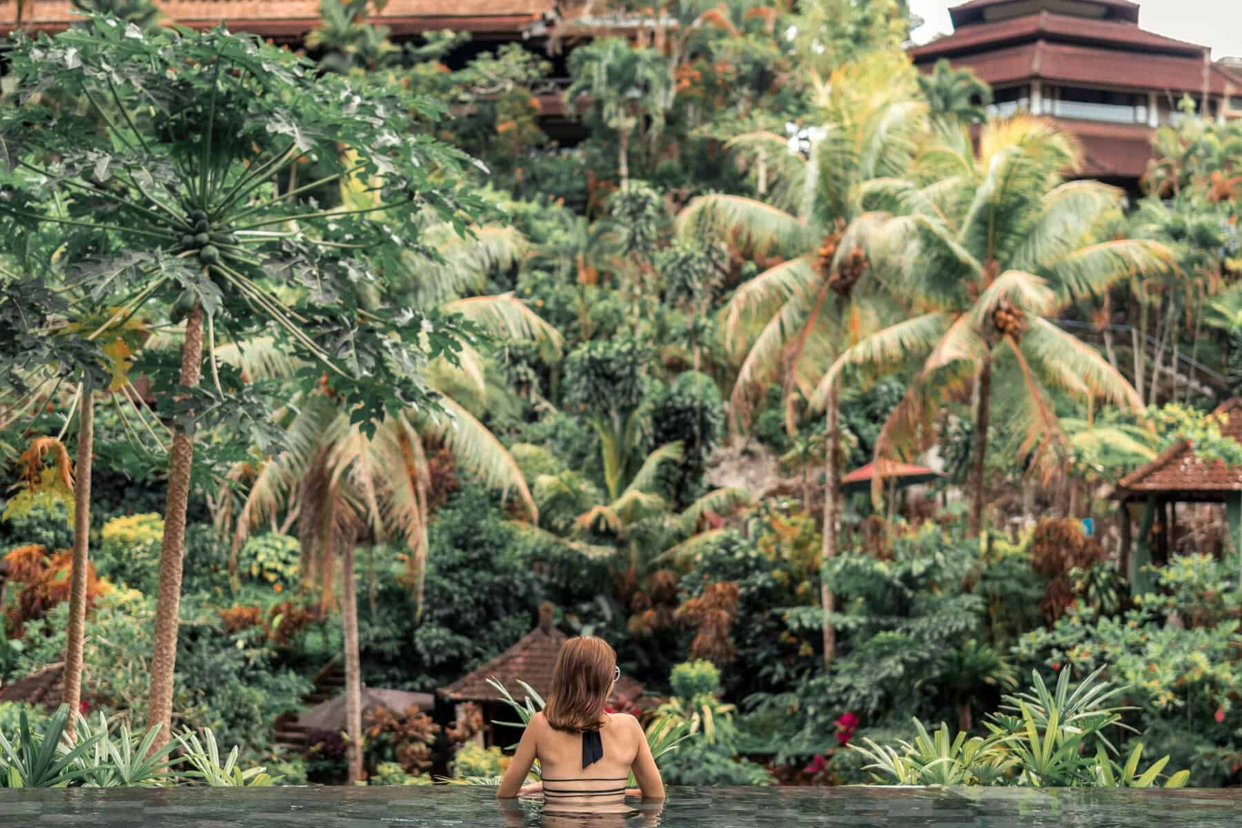 Woman in a black outfit inside a water body looking towards the greenery around her