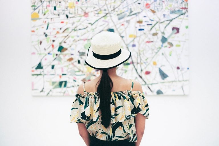 Girl in a white hat looing at a poster on the wall