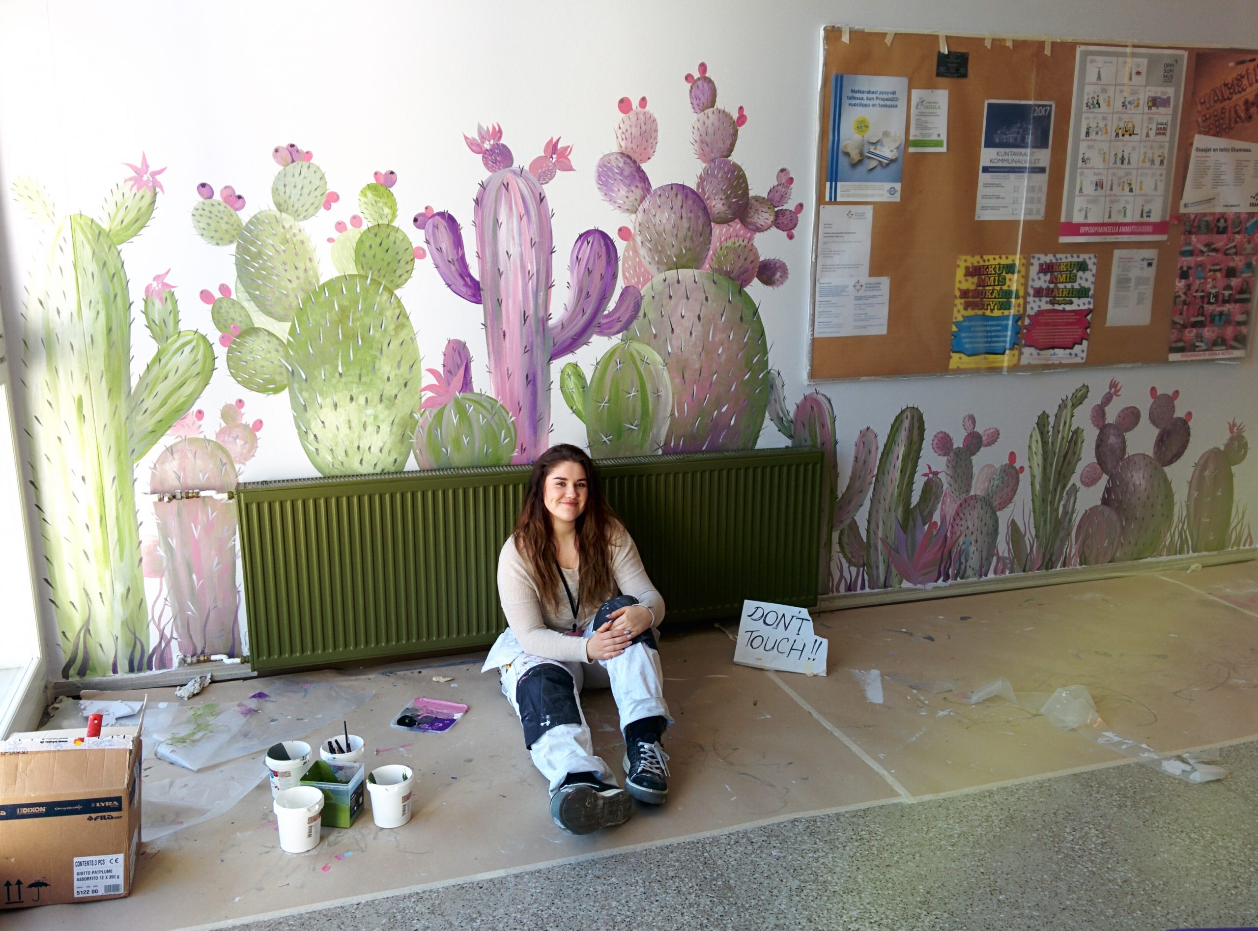 Ocean sitting on the floor near a wall painted with blue and purple cacti