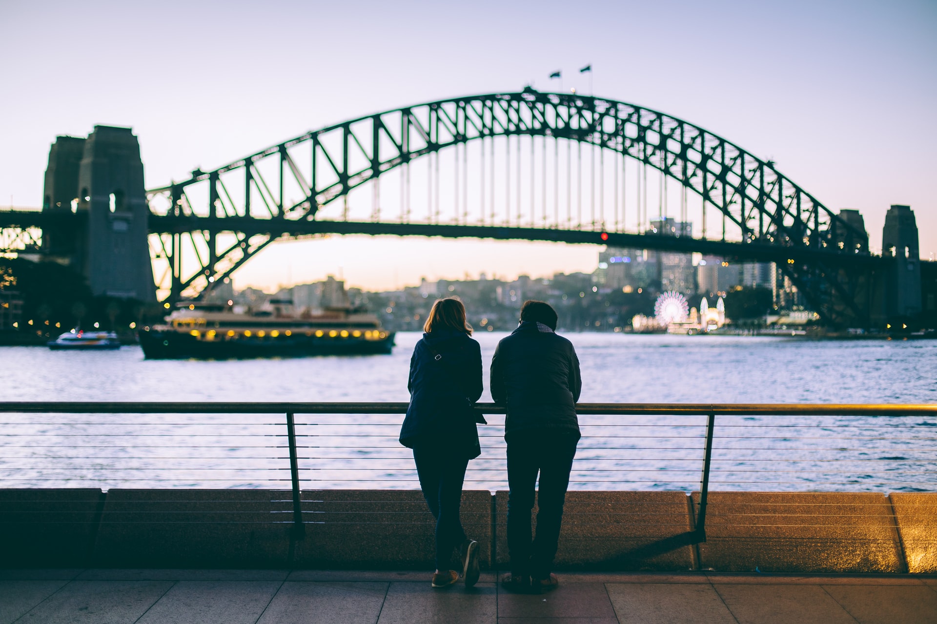 A man and a woman's silhouette against the sydney opera house in evening light