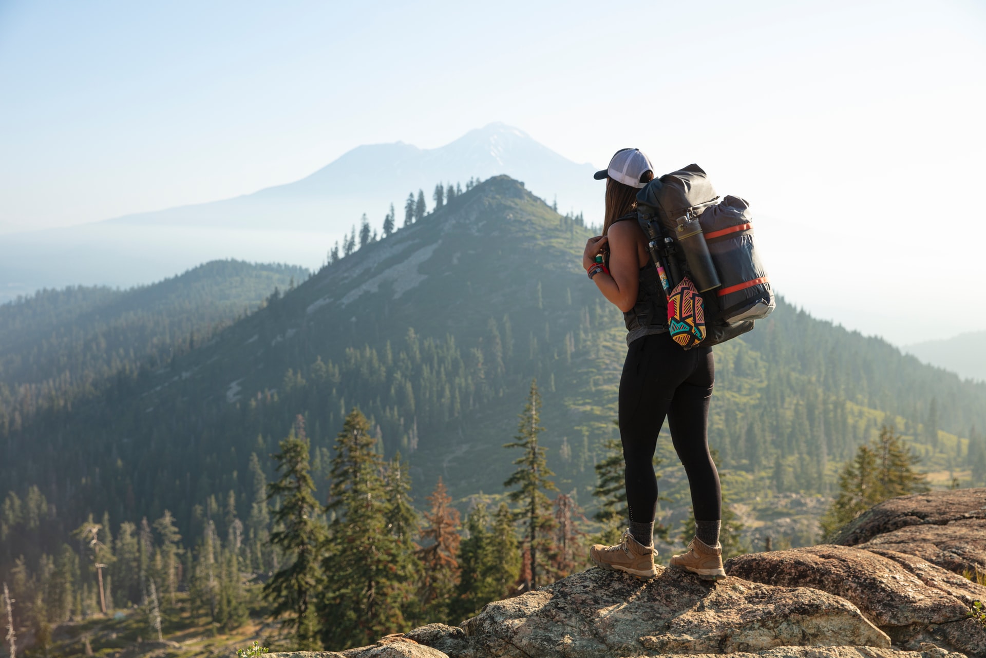 Woman with doing a solo hike with hiking gear looking out towards mountain landscape