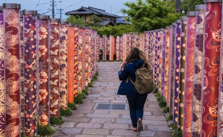 woman traveling solo in Japan walking through a temple with a purple backpack
