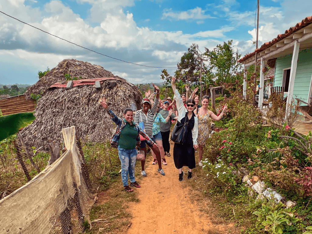 women in Vinales, Cuba valley smiling and posing next to a local home