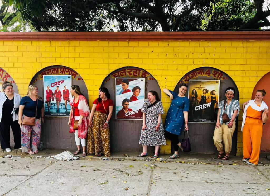 SoFe India tour group laughing in front of a yellow wall with movie posters