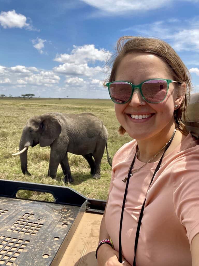 Chelsea Hottovy smiling with an elephant behind her in the Serengeti