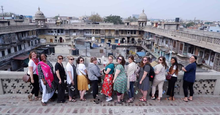 Group of female tourists smiling at a historic monument in Delhi