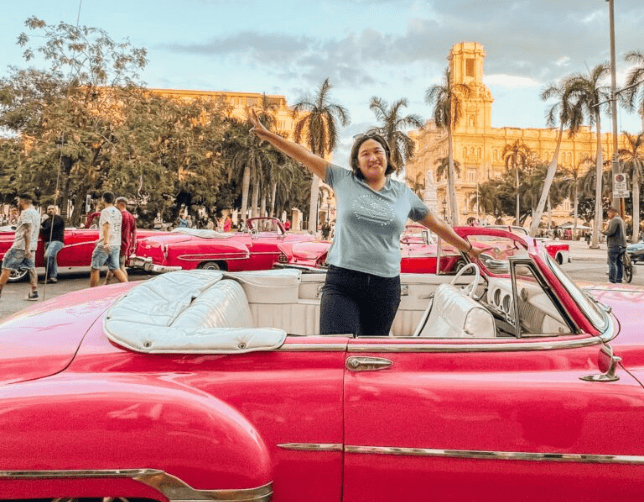 Cuba-Havana solo female traveler posing in a pink classic car in Havana, Cuba