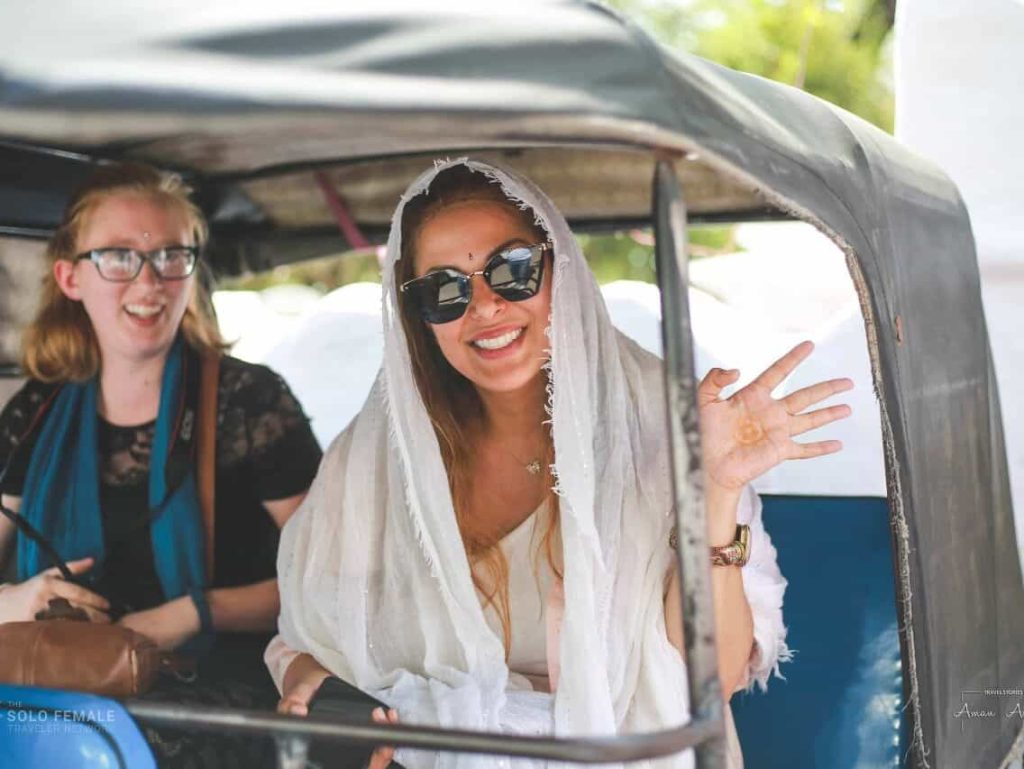 women waving from rickshaw in India