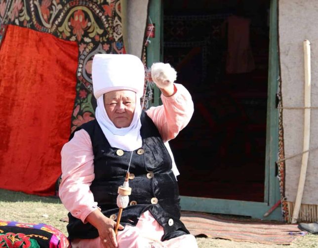 Solo female travel tour, Kyrgyzstan. Woman sitting in front of a yurt.