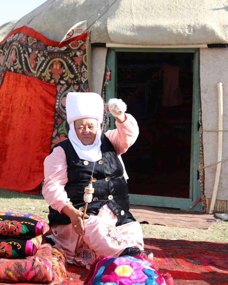 Solo female travel tour, Kyrgyzstan. Woman sitting in front of a yurt.