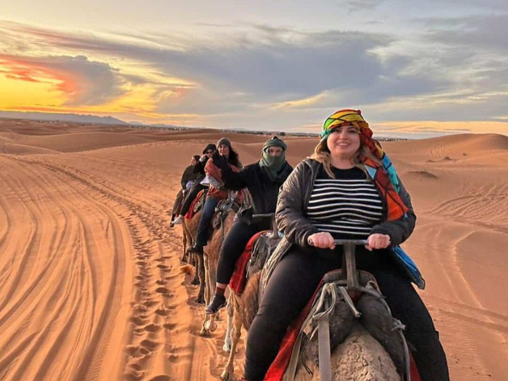 Women riding camels through the Sahara dunes on a women-only tour of Morocco