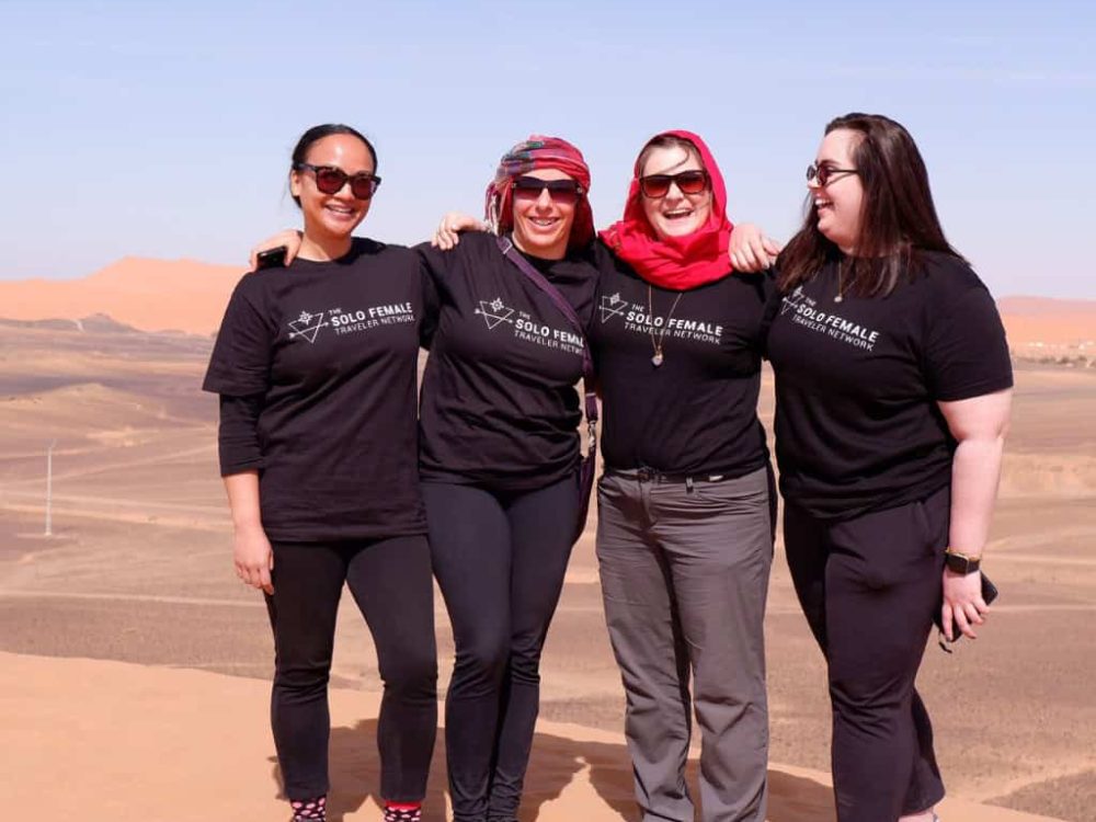 women on a women only tour in Morocco stating in the Sahara laughing